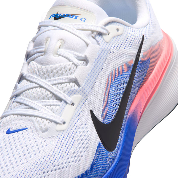 Her er en omskrevet sætning, der bruger dine produktdata: Nærbillede af Nike Pegasus 42, Herre i hvid/sort-racerblå-atomic pink – en hvid løbesko med blå og lyserøde farveovergange, et sort Nike Swoosh-logo, mesh-detaljer, hvide snørebånd og tallet „42“ trykt på tungen. Denne model er udstyret med avanceret Air Zoom-teknologi og en støttende ReactX-skum-mellemsål, der sikrer øget komfort ved hvert skridt.