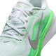 Nærbillede af Nike Pegasus 42 Dame i farvekombinationen hvid/metallisk sølv-grøn, med mesh-materiale, hvide snørebånd, sølvfarvet Swoosh, Air Zoom-enhed samt neongrønne detaljer på siden og sålen.