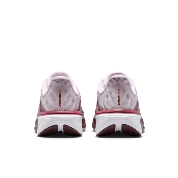 Et par Nike Pegasus 42-løbesko til kvinder i farvekombinationen Bleached Lilac/Pink Rise-Mystic Dates vises set bagfra, hvor hælen, Nike-logoet og de mønstrede såler fremhæves. Begge sko er udstyret med en Air Zoom-enhed og en ReactX-skum-mellemsål for øget komfort og præsenteres på en ren hvid baggrund.