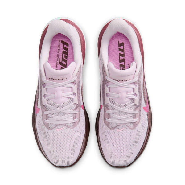 Ovenfra-billede af et par Nike Pegasus 42 Dame-løbesko i farvekombinationen Bleached Lilac/Pink Rise-Mystic Dates, med hvide snørebånd og mørkere lyserøde Nike Swoosh-logoer. Indersålerne er prydet med ordet 'pegasus' i fed skrift. Skoene, der er udstyret med en Air Zoom-enhed og en ReactX-skummellemsål for øget komfort, er placeret side om side.