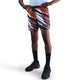 En person står med hænderne på hofterne iført en lyseblå skjorte, Nike Nk Df Stride 7In Bf Shrt Op2 shorts i White/Multi Color/Reflective Silver, sorte knæhøje Nike-sokker og sorte sportssko på en hvid baggrund.