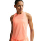 En kvinde i en ærmeløs Nike Nk Swift Nvlt Brthe Tank i Orange Pulse/Photon Dust/Reflective Silv står på en hvid baggrund og kigger til siden.