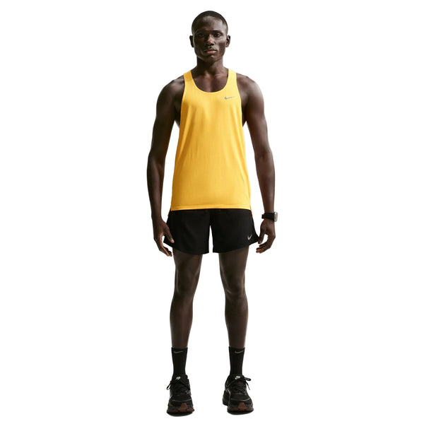 En mand står med front mod en gul ærmeløs sportstop, Nike Nk Df Stride 2In1 7In Short til mænd i sort/reflekterende sølv, sorte løbesko, sorte sokker og et sort ur på en almindelig hvid baggrund.