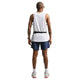 En person står med ryggen til og er iført en hvid ærmeløs skjorte, Nike Stride 2In1 7" løbeshorts til mænd i Midnight Navy/Reflective Silver, hvide sokker og sneakers, en sort bæltetaske, et ur og solbriller på en almindelig hvid baggrund.