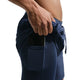 En mand iført Nike Stride 2In1 7" Running Shorts, Herre, Midnight Navy/Reflective Silv lægger sin smartphone i den lille sidelomme. Billedet fremhæver Dri-FIT-teknologien med fokus på shortsene og den hånd, der holder telefonen.