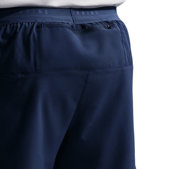 Nærbillede af ryggen på en person iført Nike Stride 5" Brief-Lined Running Shorts i Midnight Navy med elastisk linning, lille lynlåslomme og diskret RUNNING-logo, der viser den klassiske løbeshorts-stil.