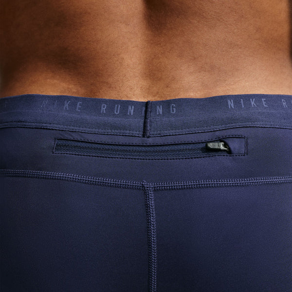 Nærbillede af det bageste taljeområde på Nike Stride Running Half Tights, Herre i farven Midnight Navy/Reflective Silv, med en lomme med lynlås og teksten »NIKE RUNNING« på linningen. Der ses bar hud over den faste linning, hvilket fremhæver dette svedtransporterende løbetøj, der er designet til optimal komfort under din løbetur.