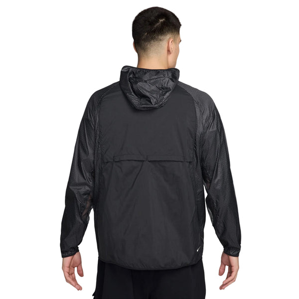 En person med kort, mørkt hår ses bagfra iført en Nike ACG Uv Aireez Jkt Herre i Black/Black/Summit White med meshpaneler på ærmer og skuldre, en løs pasform og hætten nede.