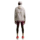 En person set bagfra, iført en Nike ACG Aireez UV Protection Jacket, Herre, Cream II /Cream II /Summit White, mørke shorts og røde sportssko.