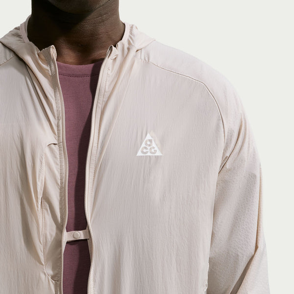 Cream II ACG Aireez UV-beskyttelsesjakke med hætte, lynlås foran, trykknaplukning og et trekantet logo på brystet.