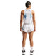 En kvinde med flettet hår og solbriller bærer en Nike Nk Arswft Dfadv Crop Tank Gx i hvid/sort/sort, hvide løbeshorts, sokker og sportssko, mens hun står med ryggen til kameraet mod en hvid baggrund.