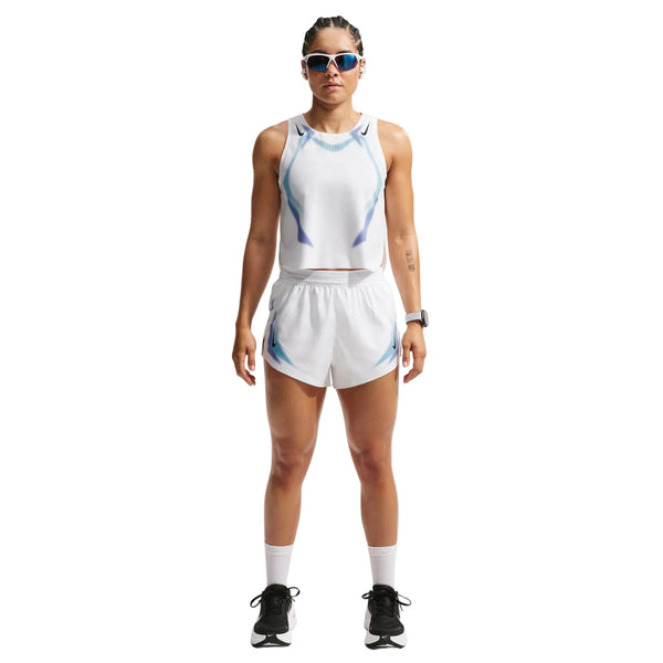 En person ser fremad iført Nike Nk Arswft Dfadv Crop Tank Gx (Dame, White/Black/Black) med matchende shorts, hvide sokker, sorte løbesko, solbriller og et smartwatch. Baggrunden er helt hvid.