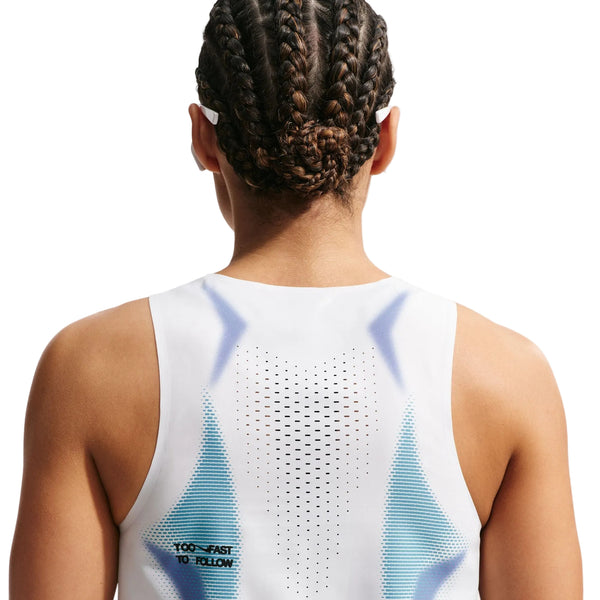 En kvinde med flettet hår ses bagfra iført en ærmeløs Nike Nk Arswft Dfadv Crop Tank Gx i hvid/sort med små perforeringer og teksten "TOO FAST TO FOLLOW" trykt nederst i venstre side.