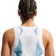 En kvinde med flettet hår ses bagfra iført en ærmeløs Nike Nk Arswft Dfadv Crop Tank Gx i hvid/sort med små perforeringer og teksten "TOO FAST TO FOLLOW" trykt nederst i venstre side.