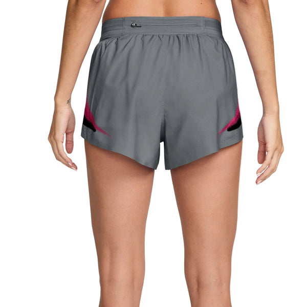 Man ser en kvinde bagfra iført Nike AeroSwift 3In Shorts Gx i farven Iron Grey/White, med armene afslappet ned langs siden. Disse løbeshorts til kvinder har en elastisk linning, en lille lynlåslomme og er fremstillet med Dri-FIT ADV-teknologi for at øge komforten og ydeevnen.