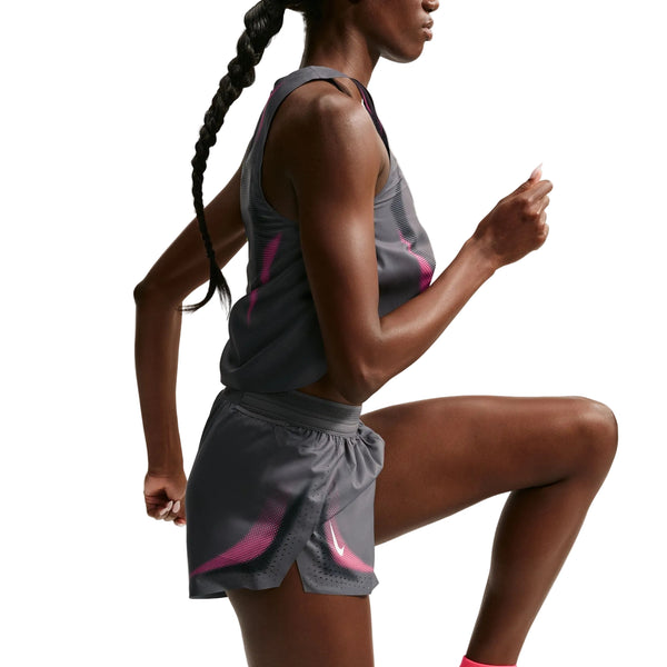 En person iført en grå sports-tanktop og Nike AeroSwift 3In Shorts Gx til kvinder i farven Iron Grey/White er afbildet i en løbestilling på en hvid baggrund. Kun overkroppen og benene er synlige, hvilket fremhæver det strømlinede design og den avancerede Dri-FIT ADV-teknologi i disse Nike-løbeshorts til kvinder.