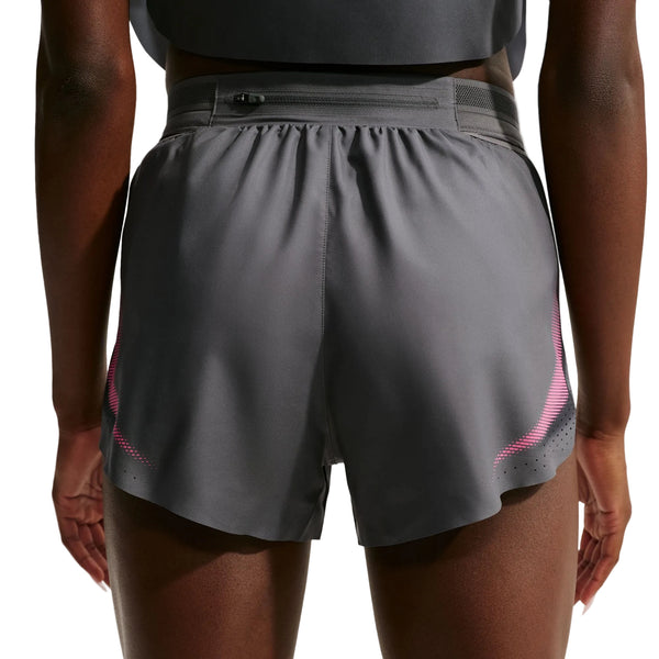 Der vises en person fra livet og ned, iført Nike AeroSwift 3In Shorts Gx til kvinder i farven Iron Grey/White. Disse løbeshorts er udstyret med Dri-FIT ADV-teknologi, der sikrer optimal komfort og ydeevne. Baggrunden er ensfarvet og neutral.