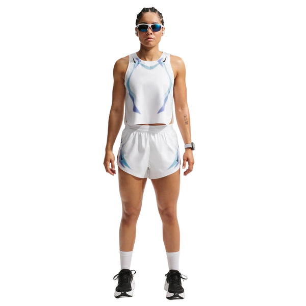 En person står med ansigtet fremad, iført solbriller, en hvid sportstank, hvide sokker, sorte løbesko og Nike Nk Arswft Dfadv 3In Short Gx Dame White/Black. Armene er langs siden, og udtrykket er neutralt.