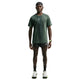 En mand står med ansigtet vendt fremad iført en Nike Stride Aero-FIT kortærmet løbetrøje til mænd i farverne sort/lysegrøn Spark/reflekterende sølv, kombineret med sorte Nike-shorts, sorte sokker, løbesko, en sort kasket og et smartwatch. Baggrunden er ensfarvet hvid.