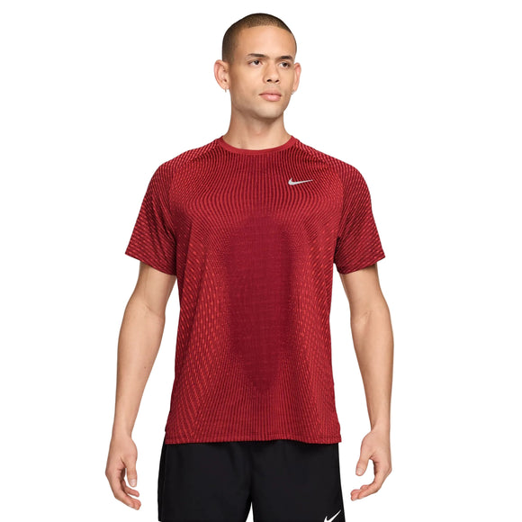 En mand står foran en ensfarvet hvid baggrund iført en Nike Stride Aero-FIT kortærmet løbetrøje til mænd i farverne Tough Red/Bright Crimson/Reflective Silver samt sorte shorts. Han står med ansigtet vendt fremad og armene afslappet ned langs siden, hvilket fremhæver denne åndbare træningstrøje, der er designet af Nike med henblik på optimal ydeevne.