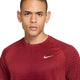 En person med kort hår og hoop-øreringe i begge ører ser direkte ind i kameraet, iført Nike Stride Aero-FIT kortærmet løbetrøje til mænd i farverne Tough Red/Bright Crimson/Reflective Silver. Den åndbare træningstrøje har en struktureret overflade med et lille, reflekterende sølvfarvet Nike-logo på venstre bryst, hvilket sikrer optimal ydeevne og komfort – ideel som løbetrøje til mænd.