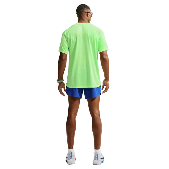 En mand står med ryggen til kameraet og har en Nike Stride Aero-FIT kortærmet løbetrøje til mænd i farverne Volt/Light Silver/Reflective Silver på, der er designet til maksimal ventilation. Han har blå sportsshorts, et smartwatch, hvide løbesko og solbriller på. Baggrunden er helt hvid.