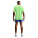 En mand står med ryggen til kameraet og har en Nike Stride Aero-FIT kortærmet løbetrøje til mænd i farverne Volt/Light Silver/Reflective Silver på, der er designet til maksimal ventilation. Han har blå sportsshorts, et smartwatch, hvide løbesko og solbriller på. Baggrunden er helt hvid.