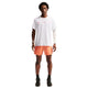 En mand ser frem for sig iført en Summit White Nike Nk Dfadv Aeroswift Gfx Ss T-shirt, orange sportsshorts, sorte sneakers, et hvidt kompressionsærme på venstre arm og et ur på højre håndled mod en almindelig hvid baggrund.