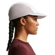 En person med fletning ses i profil mod en hvid baggrund iført en rødbrun struktureret skjorte og Nike ACG Fly Cap (Unisex, Photon Dust/College Grey/Photon Dust).