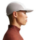 En person i profil mod en almindelig hvid baggrund bærer en Nike ACG Fly Cap (Unisex, Photon Dust/College Grey/Photon Dust) og en brun, langærmet skjorte med høj krave.