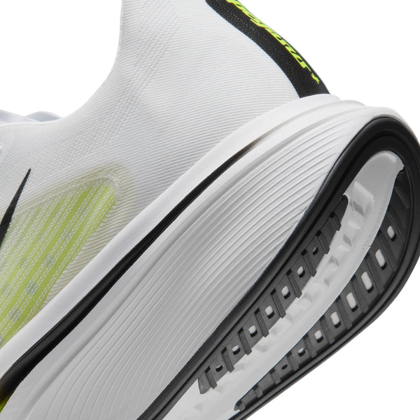 Nærbillede af et par hvide Nike Pegasus Plus 2, Herre (WHITE/BLACK-LEMON VENOM), hvor der er lagt vægt på sålen og hælen. Denne løbesko har markante detaljer i sort og Lemon Venom, hvilket fremhæver det synlige mønster på sålen og en del af overdelen. ZoomX-skum-støddæmpningen sikrer forbedret komfort og ydeevne.