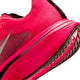 Nærbillede af et par Nike Pegasus Plus 2 i den klare farve Flash Crimson, herreløbesko i farvekombinationen Flash Crimson/Metallic Silver-Black, der viser siden og sålen med synlige mønstre, mesh-struktur og et delvist Nike-logo, der fremhæves af ZoomX-skum på en hvid baggrund.