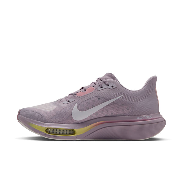 Et billede set fra siden af Nike Pegasus Plus 2 dame i farvekombinationen SILVER LILAC/SAIL-PARTICLE ROSE-FENNEL viser en lyselilla overdel i mesh med et hvidt Swoosh-logo, lyserøde detaljer, en synlig luftpude i sålen, »ZoomX-skum«-logoet på mellemsålen og en gul detalje tæt på sålen.