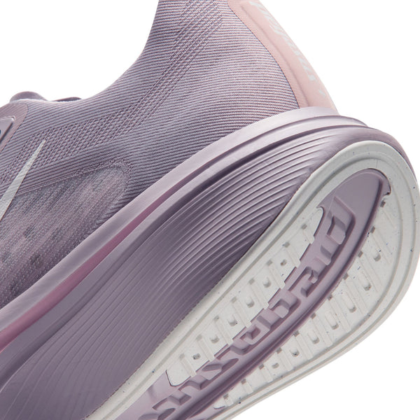 Nærbillede af siden og sålen på en Nike Pegasus Plus 2-løbesko til kvinder i farvekombinationen SILVER LILAC/SAIL-PARTICLE ROSE-FENNEL, der fremhæver ZoomX-skumstøddæmpningen i den hvide og lyserøde sål, med strukturerede detaljer på siden og et markant mønster på sålen.