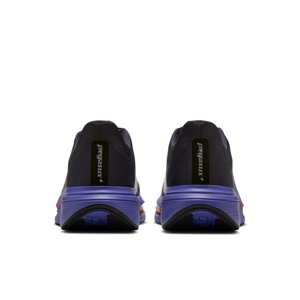 Bagfra-billede af to Nike Pegasus Plus 2-løbesko i farverne Gridiron og Persian Violet, med mørke overdele, lilla mellemsåler og teksten pegasus+ trykt på hælflapperne.