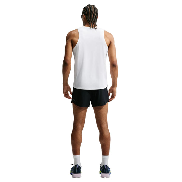 En person med flettet hår står med ryggen til og er iført en ærmeløs hvid T-shirt, hvide sokker, sorte sportssko og Nike Aero-FIT 5" løbeshorts med indvendig underbuks til mænd i sort/reflekterende sølv – løbeshorts designet med innovativ ventilationsteknologi – foran en ensfarvet hvid baggrund.