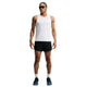 En person står med ansigtet vendt fremad og er iført en hvid, ærmeløs sportstrøje, Nike Aero-FIT 5" løbeshorts med indvendig linning til mænd i farverne sort/reflekterende sølv, hvide sokker, sorte løbesko med ventilationsteknologi samt solbriller. Baggrunden er ensfarvet hvid.