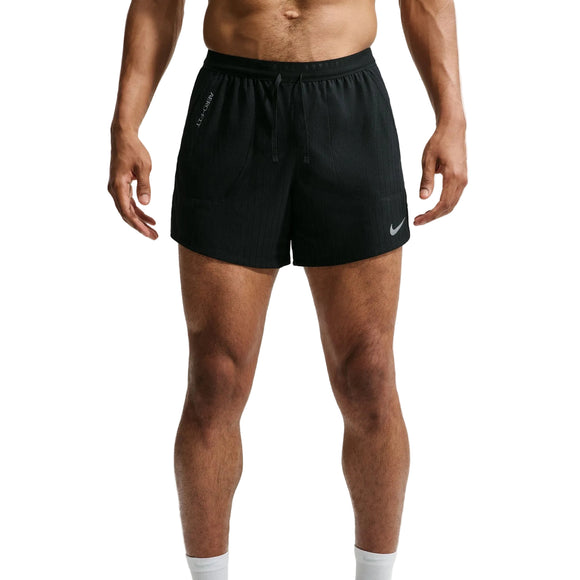 En mand står med ansigtet vendt fremad iført sorte Nike Aero-FIT 5" løbeshorts med indvendig underbuks (herre) i farven sort/reflekterende sølv. Løbeshortsene er udstyret med ventilationsteknologi, snøre i taljen og Nike-logoet på venstre ben. Kun hans overkrop og ben er synlige.
