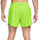 Der ses en person fra livet og ned, iført lysegrønne Nike Aero-FIT 5" løbeshorts med indvendig underbuks, Herre, i farven Volt/Reflective Silver – et stilfuldt par løbeshorts til mænd med snøre – stående med armene afslappet ned langs siden.