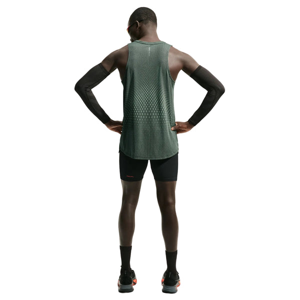 En person står med ryggen til, hænderne i siden, iført en Nike Aero-FIT løbetrøje til mænd i farverne sort/lysegrøn spark/reflekterende sølv – designet til maksimal ventilation – kombineret med sorte armvarmere, sorte shorts, sorte sokker og sorte løbesko, foran en hvid baggrund.