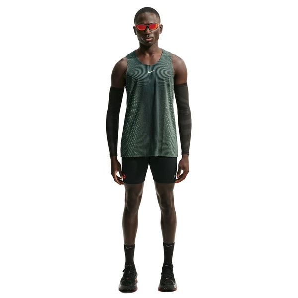 En person iført en sort og lysegrøn Spark Nike Aero-FIT løbetrøje til mænd, der er designet til maksimal ventilation som en letvægts-løbetrøje, samt sorte armvarmere, sorte shorts, sorte sokker, sorte sko og røde solbriller står med ansigtet vendt fremad foran en hvid baggrund.