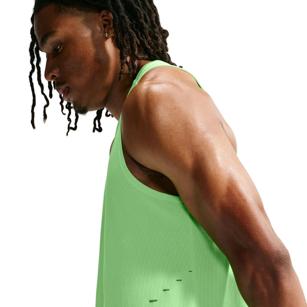 En mand med mellemlange dreadlocks har en Nike Aero-FIT løbetanktop til mænd i farverne Volt/Light Silver/Reflective Silver på. Han står vendt mod venstre og kigger nedad foran en hvid baggrund.