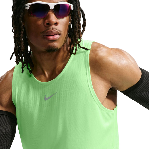 En mand iført en Nike Aero-FIT løbetanktop (Herre, Volt/Light Silver/Reflective Silver) med maksimal ventilation, med sorte ærmer og reflekterende sportsolbriller. Tanktoppen har et lille Nike-logo foran. Hvid baggrund.