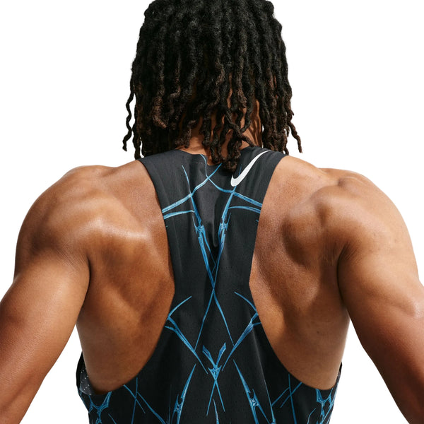Der ses en muskuløs mand set bagfra, iført Nike AeroSwift Printed Running Singlet, Herre, Sort/Hvid. Singletten har et blåt geometrisk mønster, og baggrunden er ensfarvet hvid.