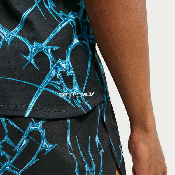 Et nærbillede af en person, der bærer Nike AeroSwift Printed Running Singlet, Herre, i sort/hvid, med blå abstrakte mønstre og teksten »DRI-FIT ADV« trykt i hvidt på trøjen.