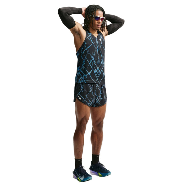 En person står med hænderne bag hovedet iført en sort og blå tanktop, Nike AeroSwift Printed 2" løbeshorts med indvendig underbuks til mænd i sort/hvid, sorte armvarmere, strømper, løbesko og solbriller foran en ensfarvet hvid baggrund.