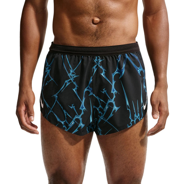 En person iført Nike AeroSwift Printed 2" løbeshorts med underbukser, herre, sort/hvid. Billedet er beskåret, så man kan se personens overkrop og lår mod en ensfarvet baggrund.