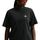 En person iført en sort Nike ACG Dri-FIT T-shirt til kvinder med et lille hvidt trekantet logo på brystet og røde solbriller står foran en hvid baggrund.