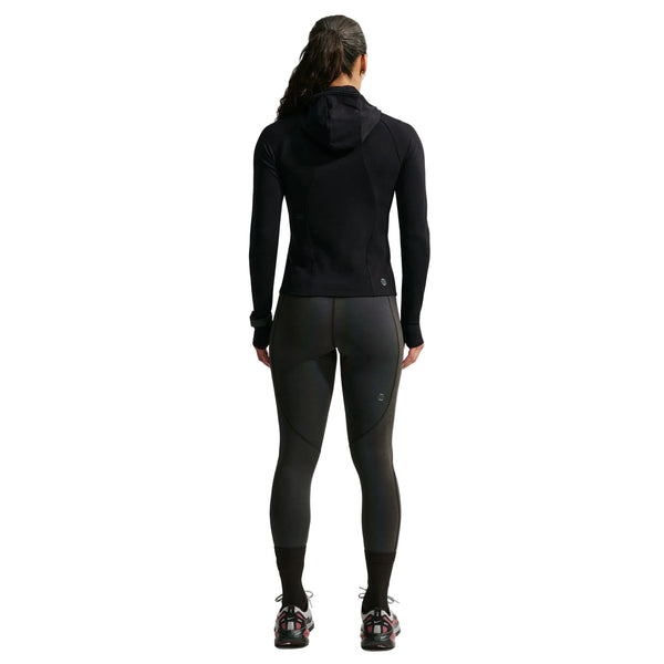 En person set bagfra, iført en sort Nike Wool Running Mid-Layer Top, Dame, mørke leggings, sorte sokker og sportssko.