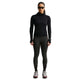 En person iført en sort Nike Wool Running Mid-Layer Top, Dame-model med manchetter med tommelfingerhuller, sorte leggings og grå løbesko.